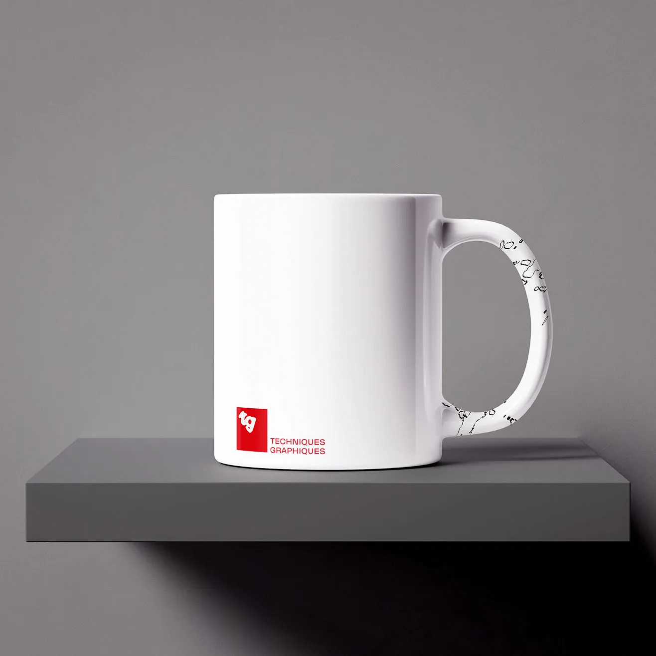 Mug blanc avec le logo rouge de Techniques Graphiques posé sur une étagère